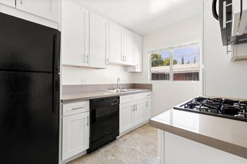 A kitchen with black appliances and white cabinets.